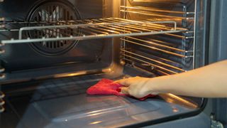 Woman wiping inside of oven