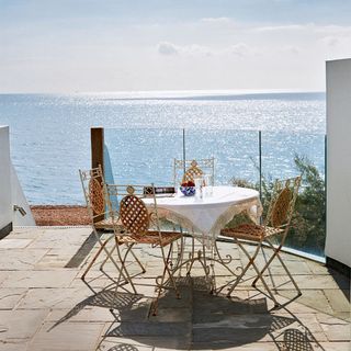 sunny terrace with round table and chairs with sea view