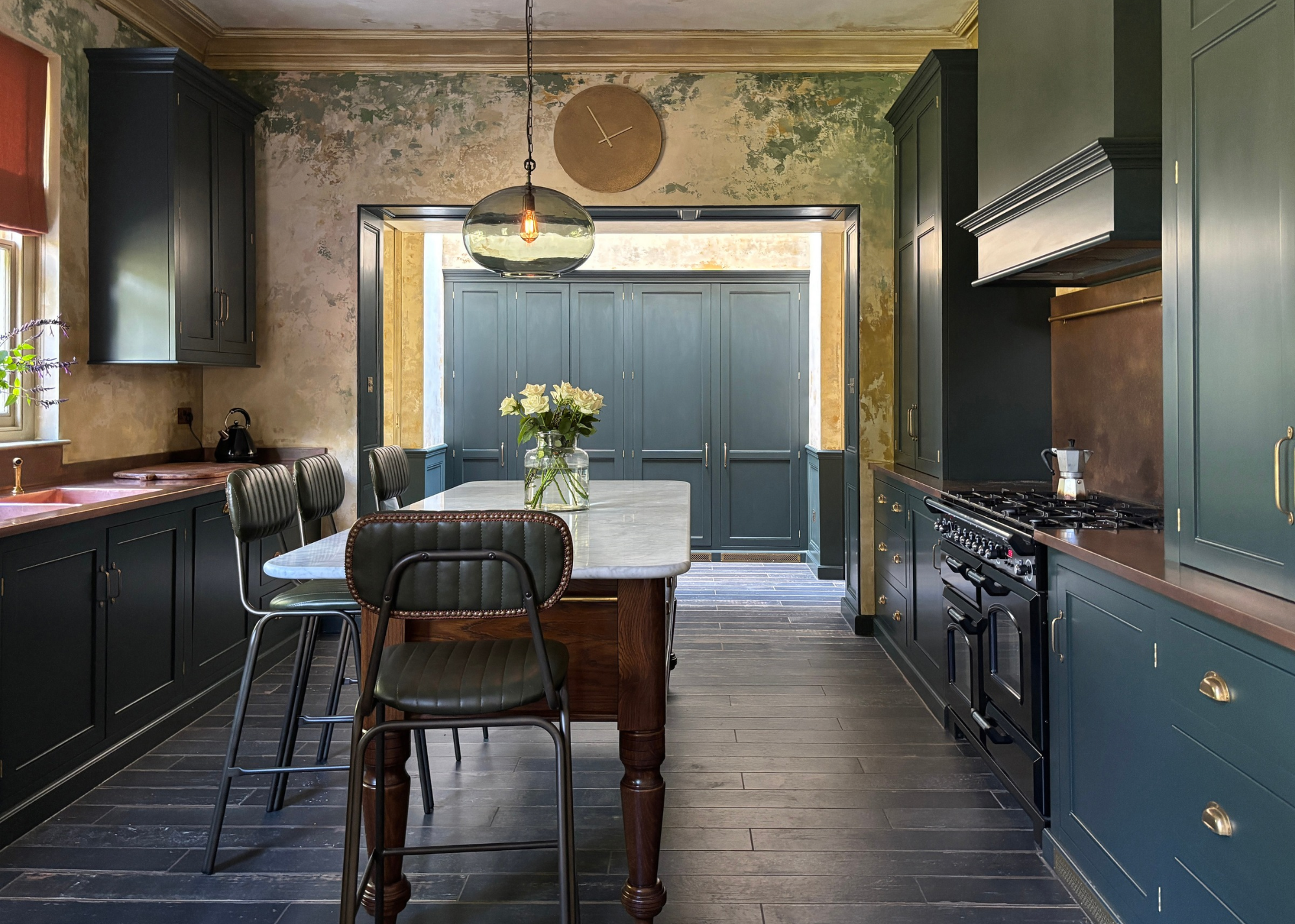 period kitchen with dark navy cabinetry, a wooden island at the centre and glass pendant lights
