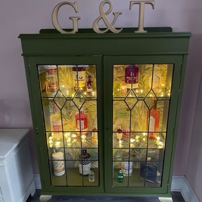 Restored cabinet with a beautiful display of gin bottles and an inside light with a "G&T" sign at the top