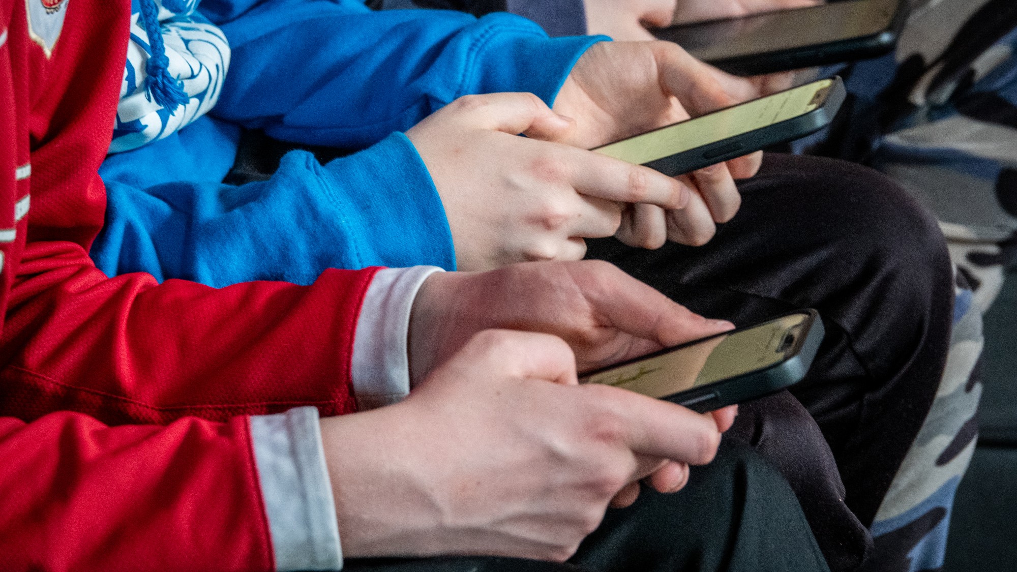 Close-up on the hands of boys looking at their smartphones