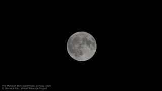 a fully illuminated moon against a black backdrop of sky.