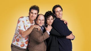 Kramer, George, Elaine and Jerry hugging each other from behind and smiling at the camera.