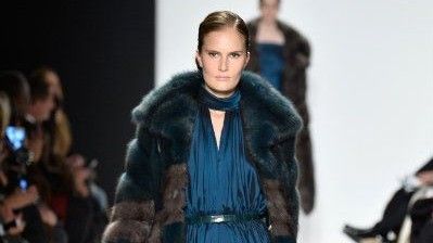 Model wearing fur coat, walking on catwalk