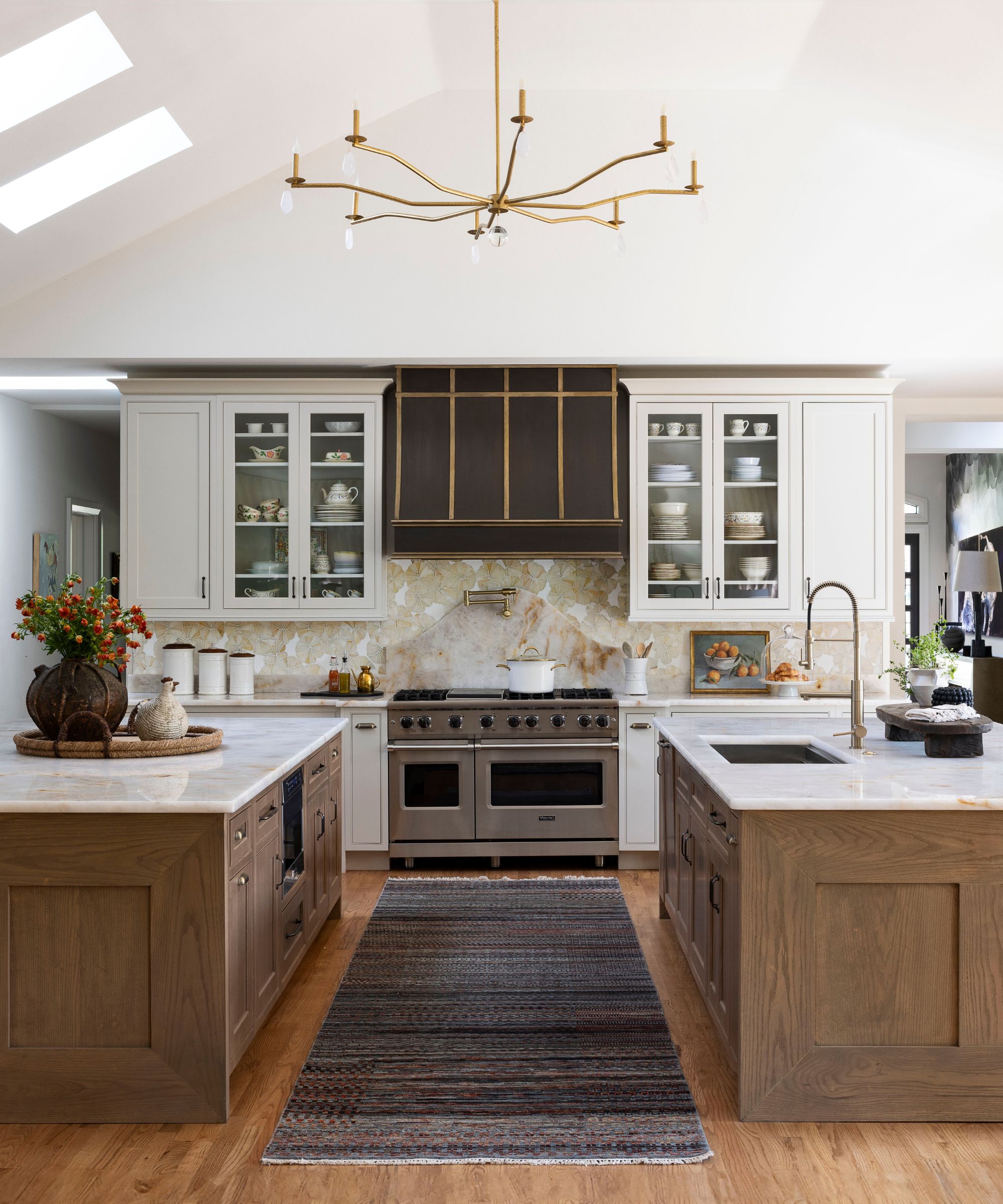 Large white kitchen with two wooden islands and a grey stripped rug in between