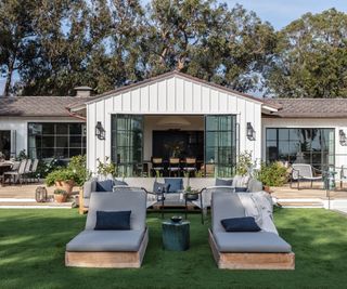 exterior of white wooden paneled house with sun loungers