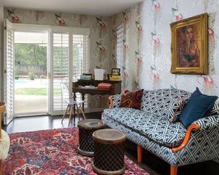 Living room with patterned wallpaper, patterned sofa and patterned rug, desk and chair in corner