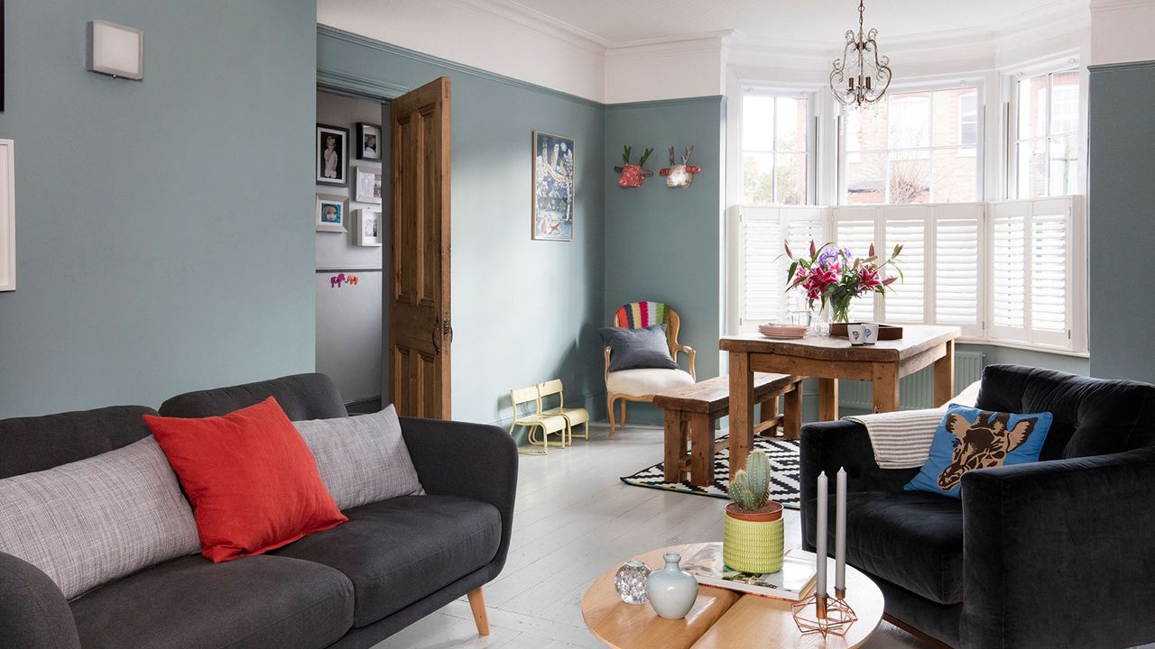 blue wall with wooden flooring and cushions on black sofa with candles on table