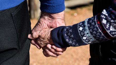 An elderly couple holding hands