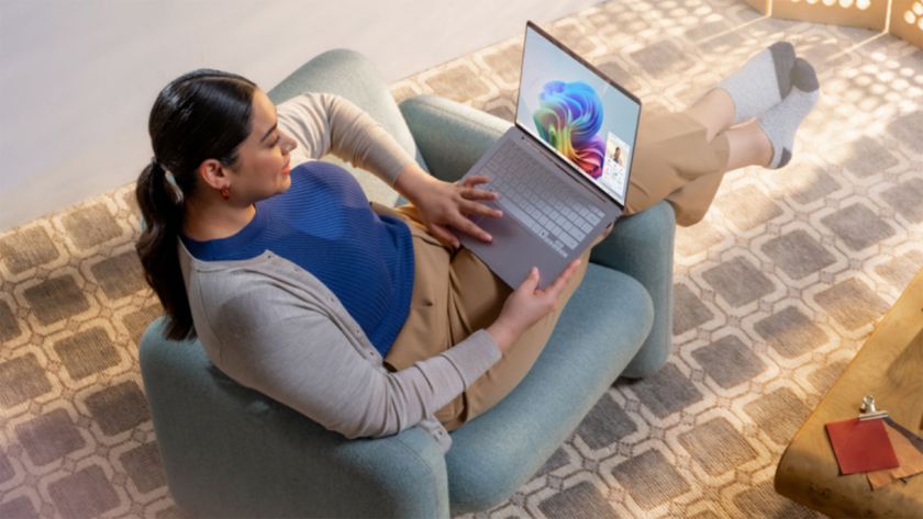 A woman sitting in a chair looking at a Windows 11 laptop