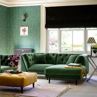 Dark green sofa, large window, green painted walls in living room