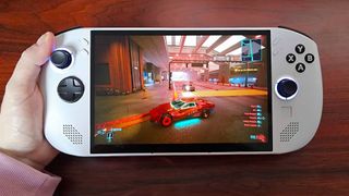 Hand holding Lenovo Legion Go S with Cyberpunk 2077 gameplay on screen featuring red sports car on road.