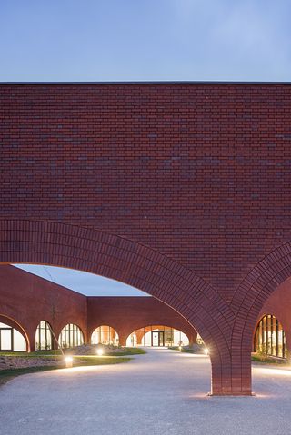 external detail of brick wall at dusk at Hermès' Maroquinerie de Louviers leather production facility by Lina Gotmeh