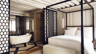 open plan bathroom and bedroom with black and white wooden sliding decorative screens to divide the bathroom from bedroom