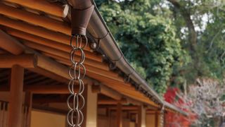 section of wooden roof with guttering and rain chain