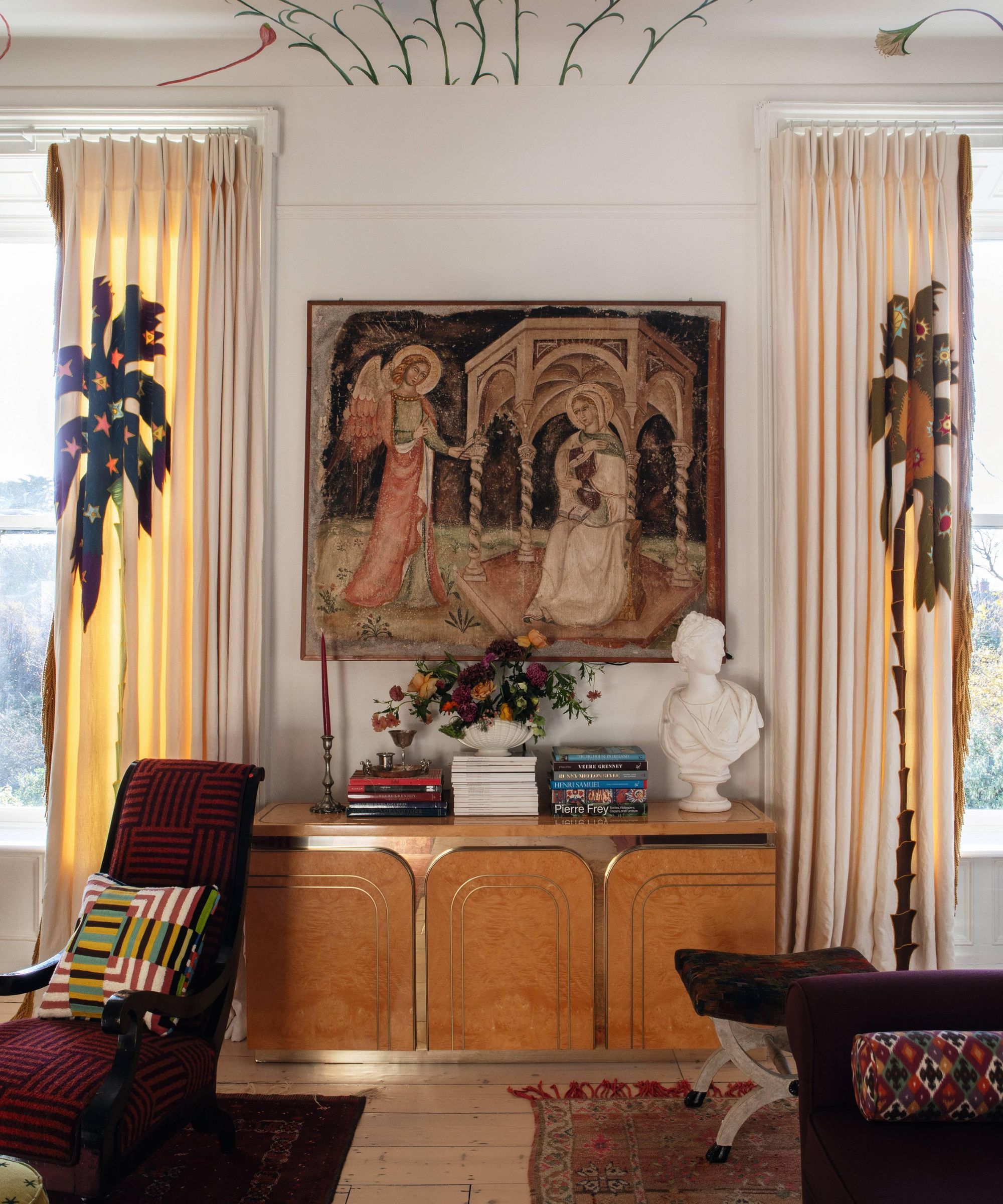 a grand drawing room in dublin with a painted mural ceiling, antique burl wood credenza with a vintage tapestry and statement drapes with palm tree design