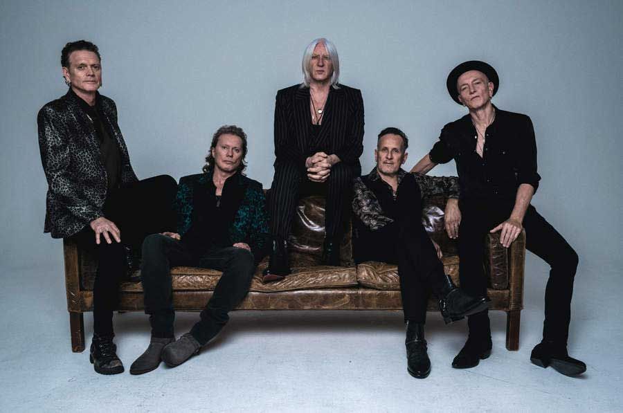 Def Leppard seated on a leather sofa