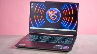 Three-quarter view of MSI Cyborg 15 A13U open on desk on a pink background 