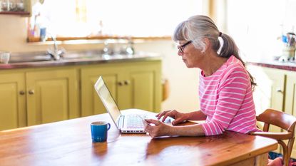 A senior woman on her laptop computer in her kitchen