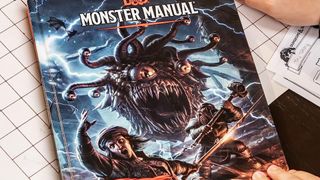 Monster Manual book being held over a table and grid