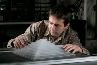 Bogdan Popa, a research scientist in electrical and computer engineering, shows off the 3D acoustic cloak he helped design and build as a member of Steven Cummer’s laboratory.