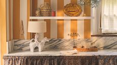 A striped yellow kitchen with a playful cowboy lamp on the marble countertop 