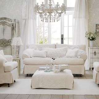 French country living room with white furniture and chandelier light