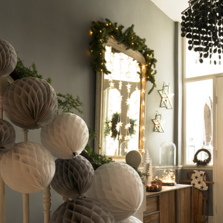 Hallway and staircase, banisters decorated with paper Christmas decorations, hall mirror decorated with foliage and Christmas lights.