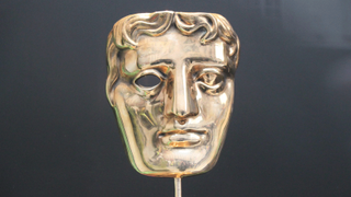A close up of the face of the golden BAFTA trophy