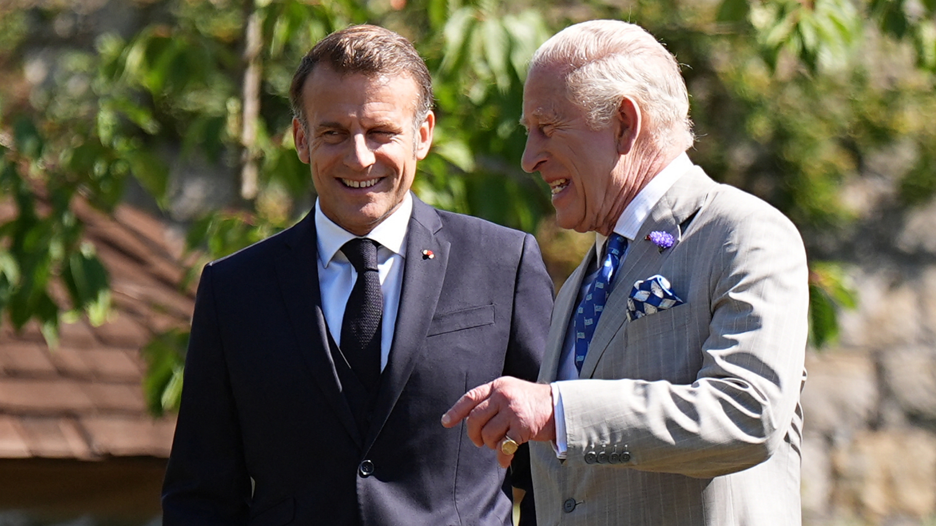 King Charles and Emmanuel Macron laughing in suits outside