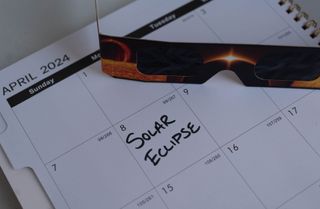 A calendar with April 8th marked with "Solar Eclipse", next to solar eclipse glasses