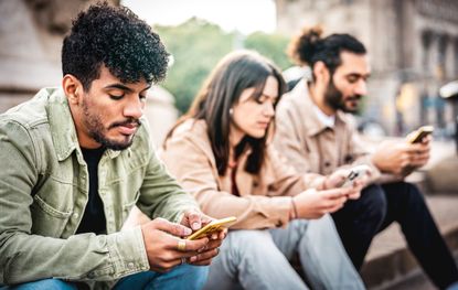 Group of young people using mobile smart phone looking fed up