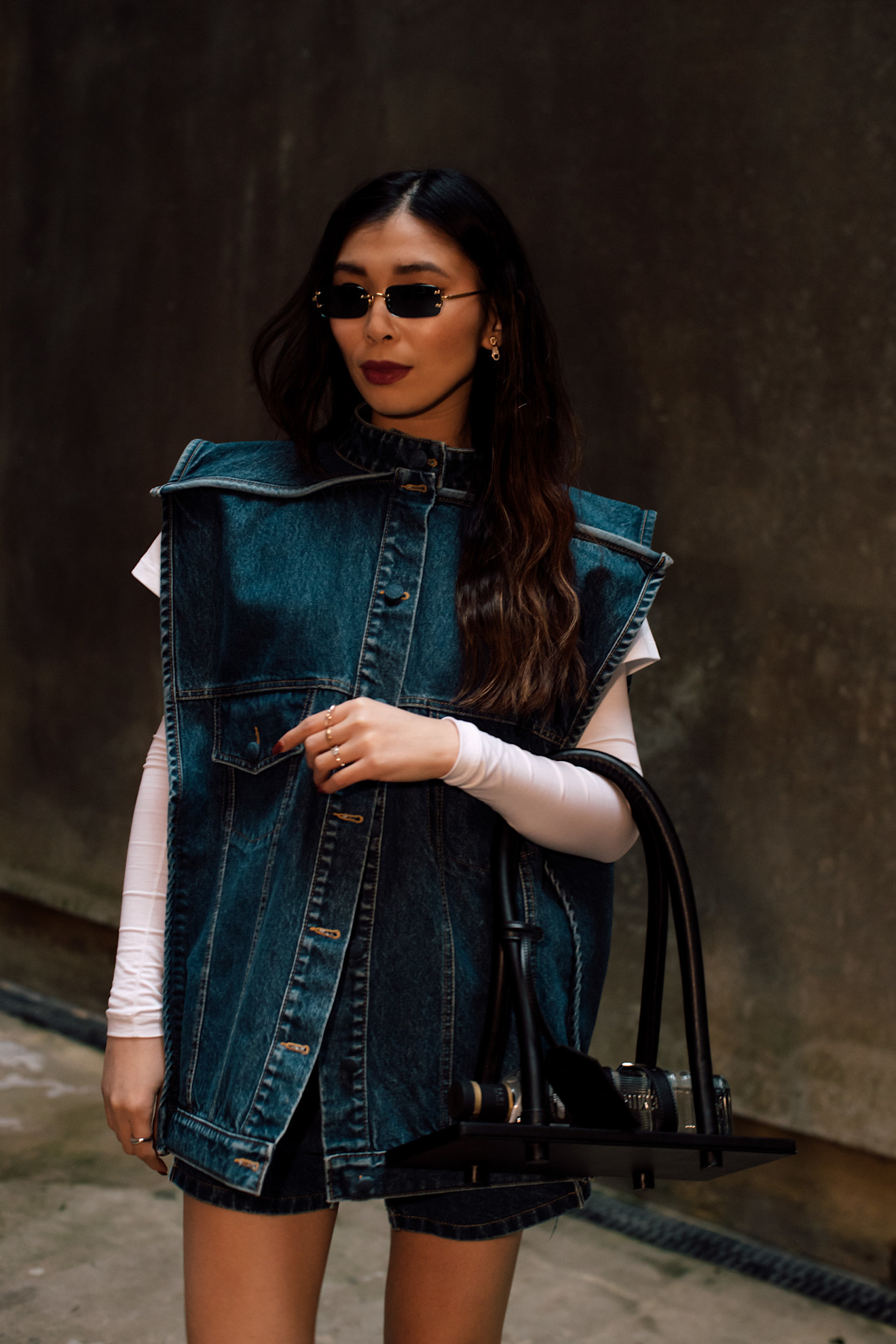 a woman in a denim vest with long dark hair and sunglasses