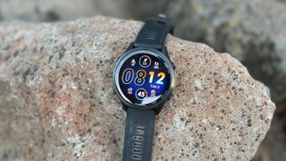 The Garmin Forerunner 970 sitting on a rock, showing a default watch face.
