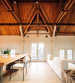 Loft with wood ceilings, a long table and chairs, and cream sofa at the Prinsengracht venue