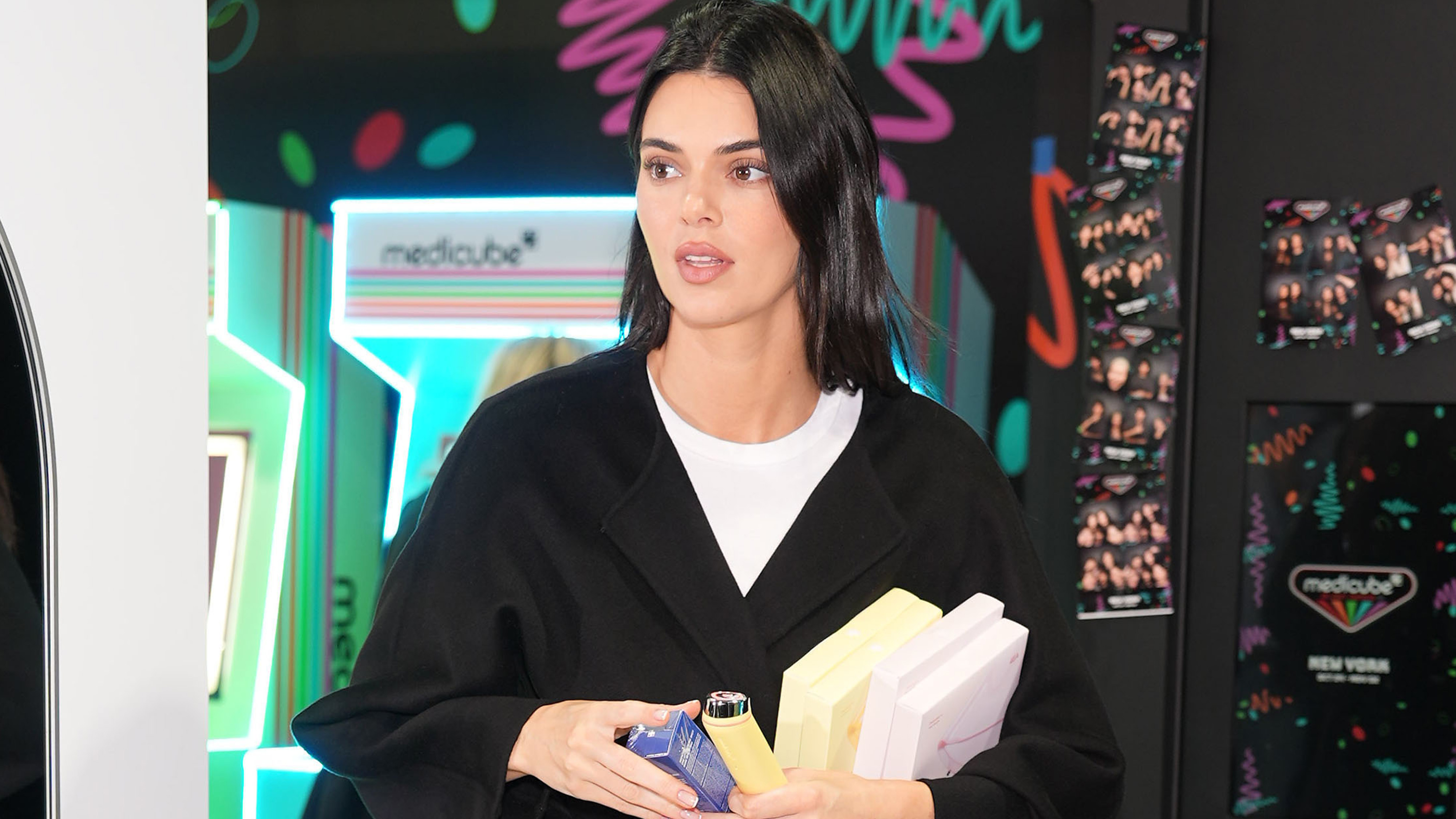 Kendall jenner wears a white tee and a black coat.