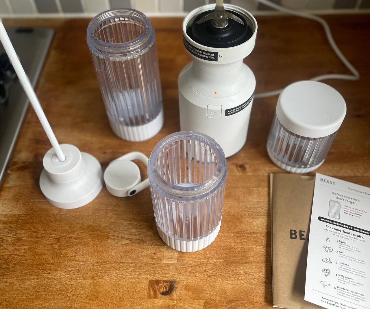 The Beast mighty 850 blender on a wooden counter with the three sized blender cups.