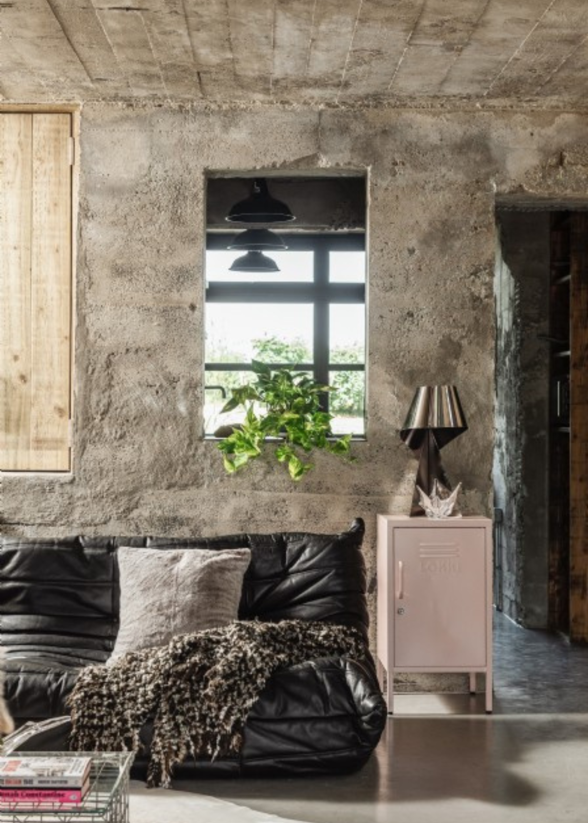 black leather togo sofa with cushions and blankets in a cool concrete bunker