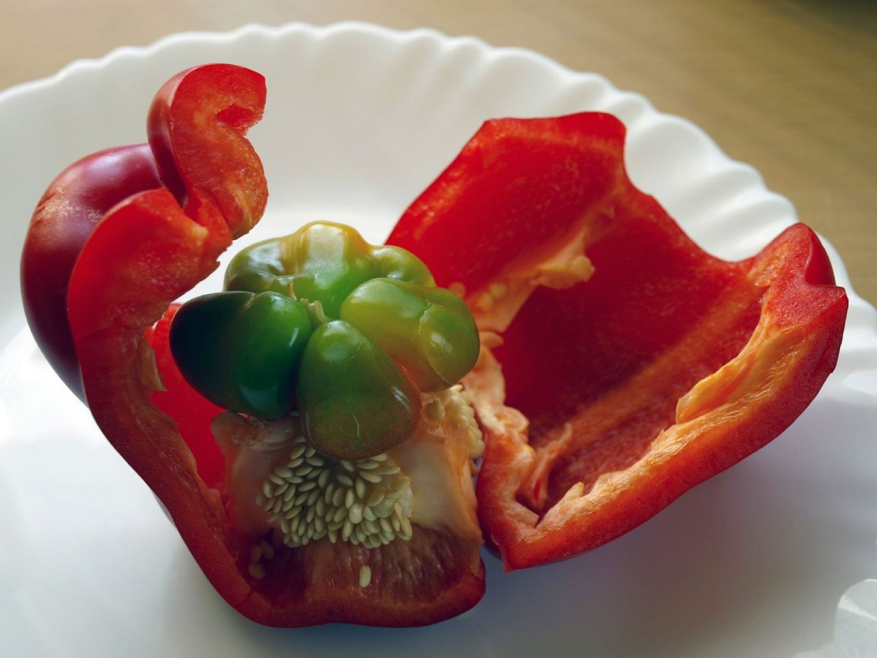 Little Green Pepper Growing Inside Of Large Red Pepper