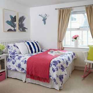 bedroom with white wall white bed with floral designed cushion white window and cream coloured flooring