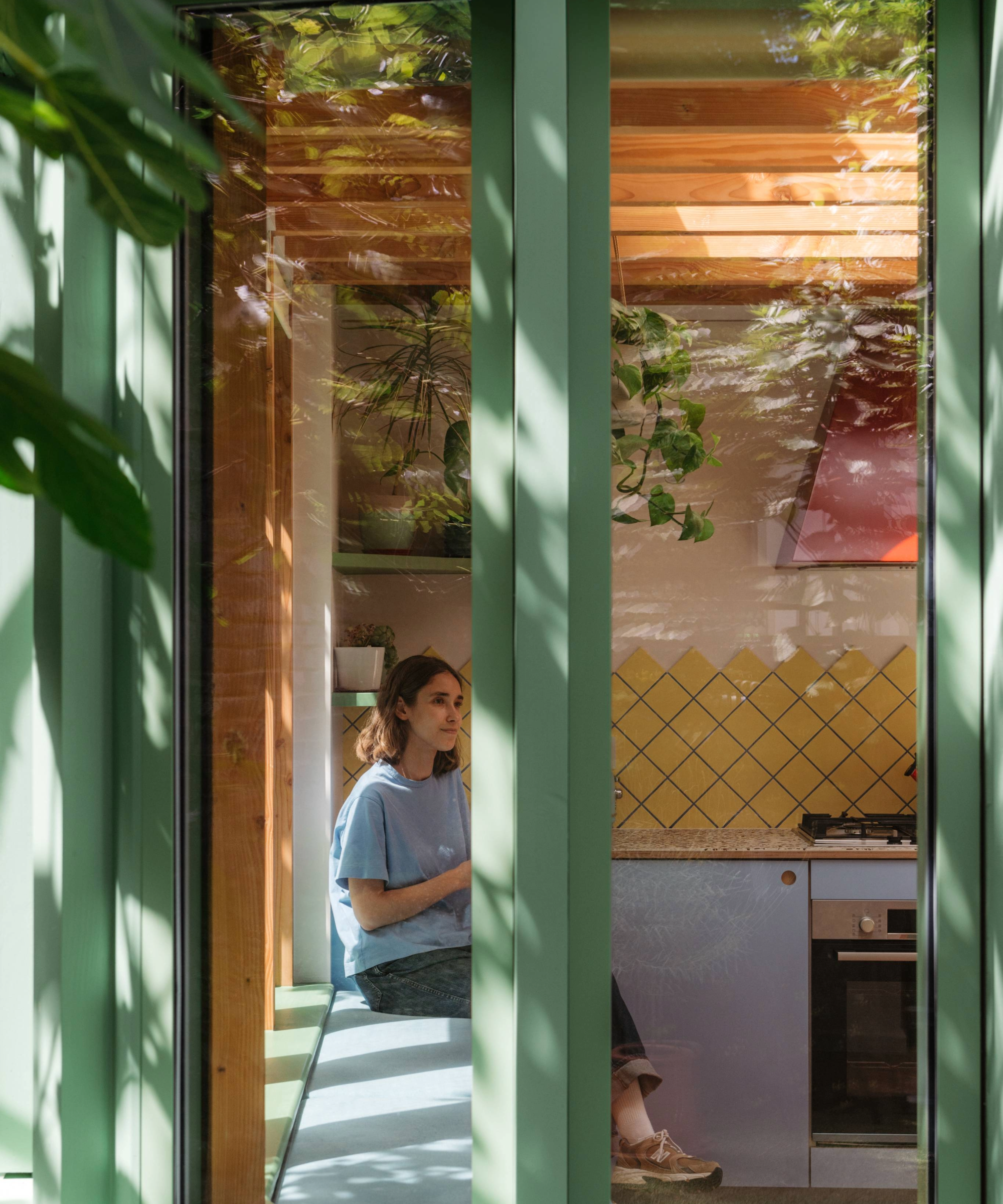 View from the window inside the kitchen with the homeowner sitting on the window nook