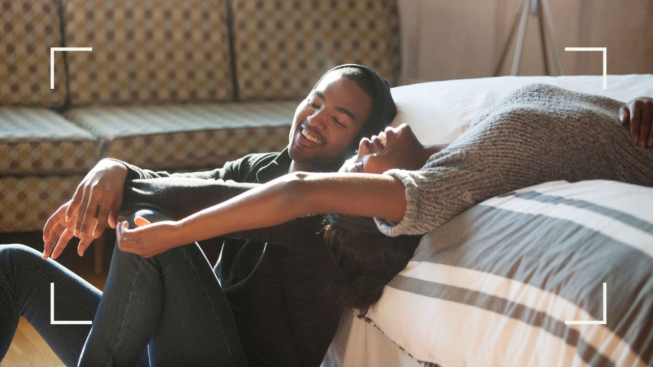 Man sitting off the edge of a bed and woman lying down on bed behind him to represent the edge of heaven sex position