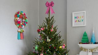 Christmas tree with a pink bow topper to show how to decorate a Christmas tree with an alternative tree topper