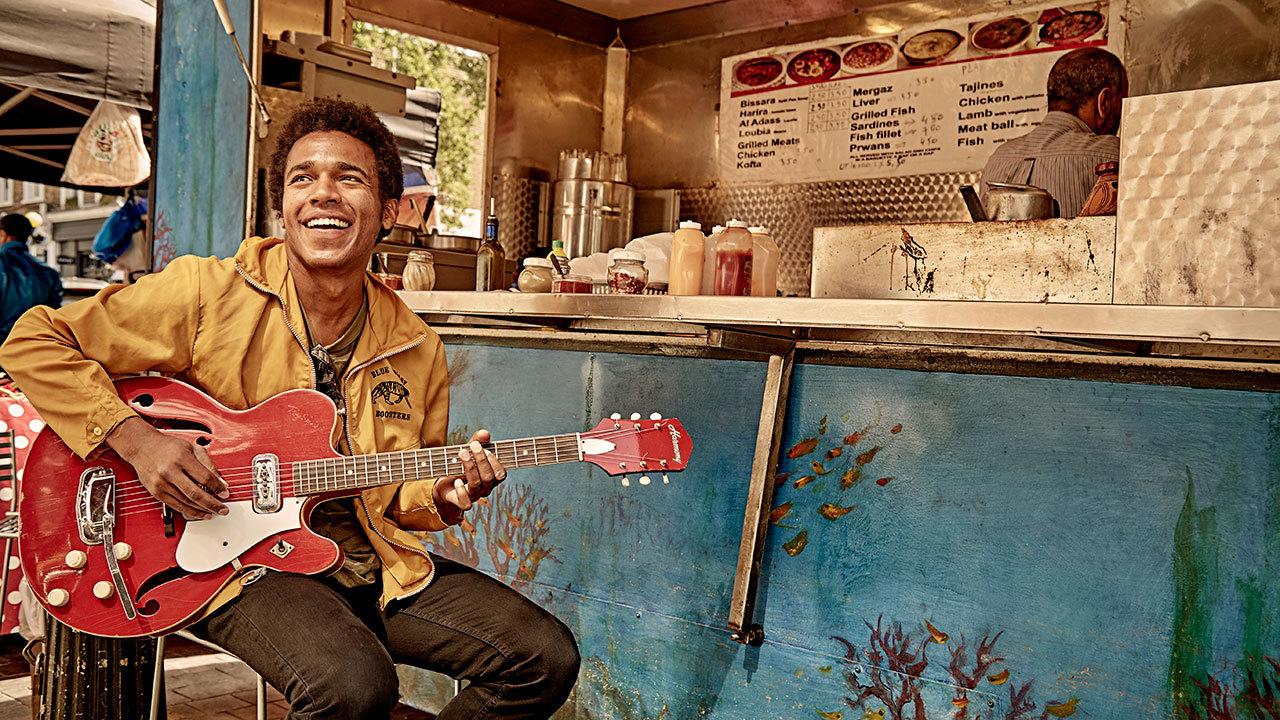 A shot of Benjamin Booker holding his guitar at a food truck