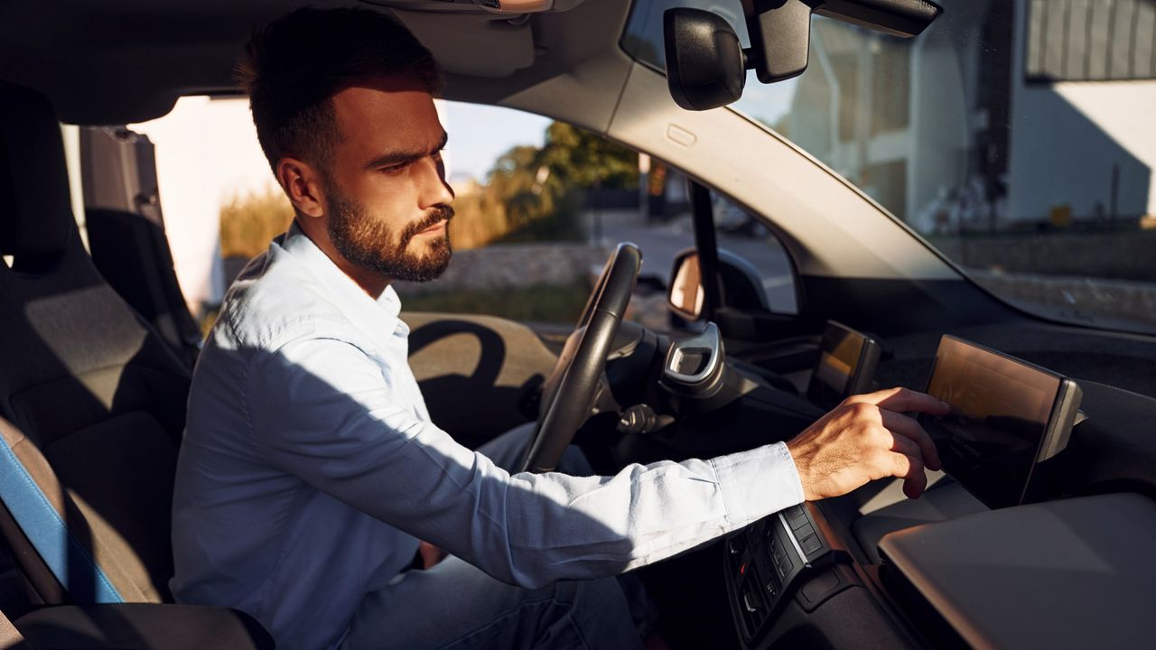 man using control panel in electric car