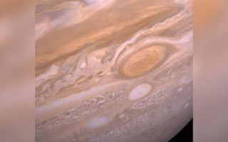 Close up images of Jupiter's Great Red Spot, a large sandy orange oval on the planet, surrounded by wispy beige, orange and rusty red bands.