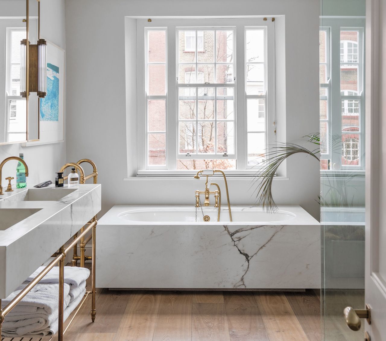 A bathroom with a marble bathtub and wooden floor