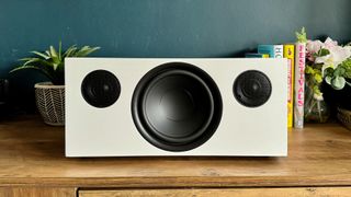 Audio Pro C20 wireless speaker pictured straight on from front, on wooden furniture