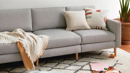 The Burrow Nomad sofa in grey upholstery with a throw and pillow