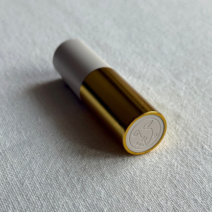 Image showing the Violette FR Bisou Balm in the shade laying at an angle against an off-white linen background
